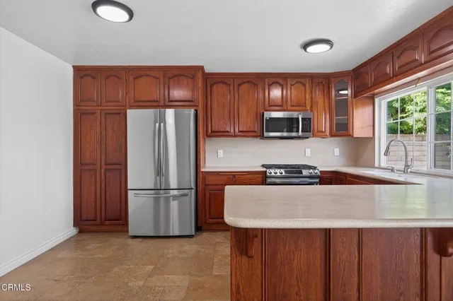 a kitchen with granite countertop wooden cabinets a refrigerator and a sink