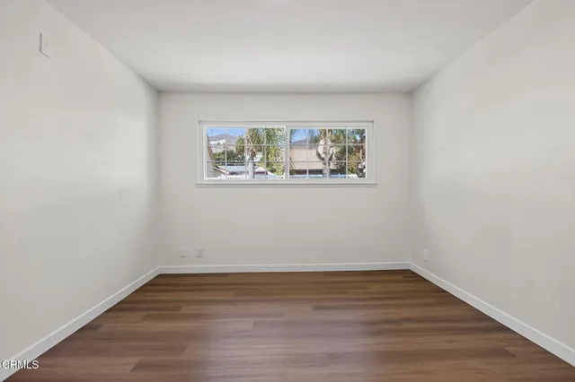 an empty room with wooden floor and window