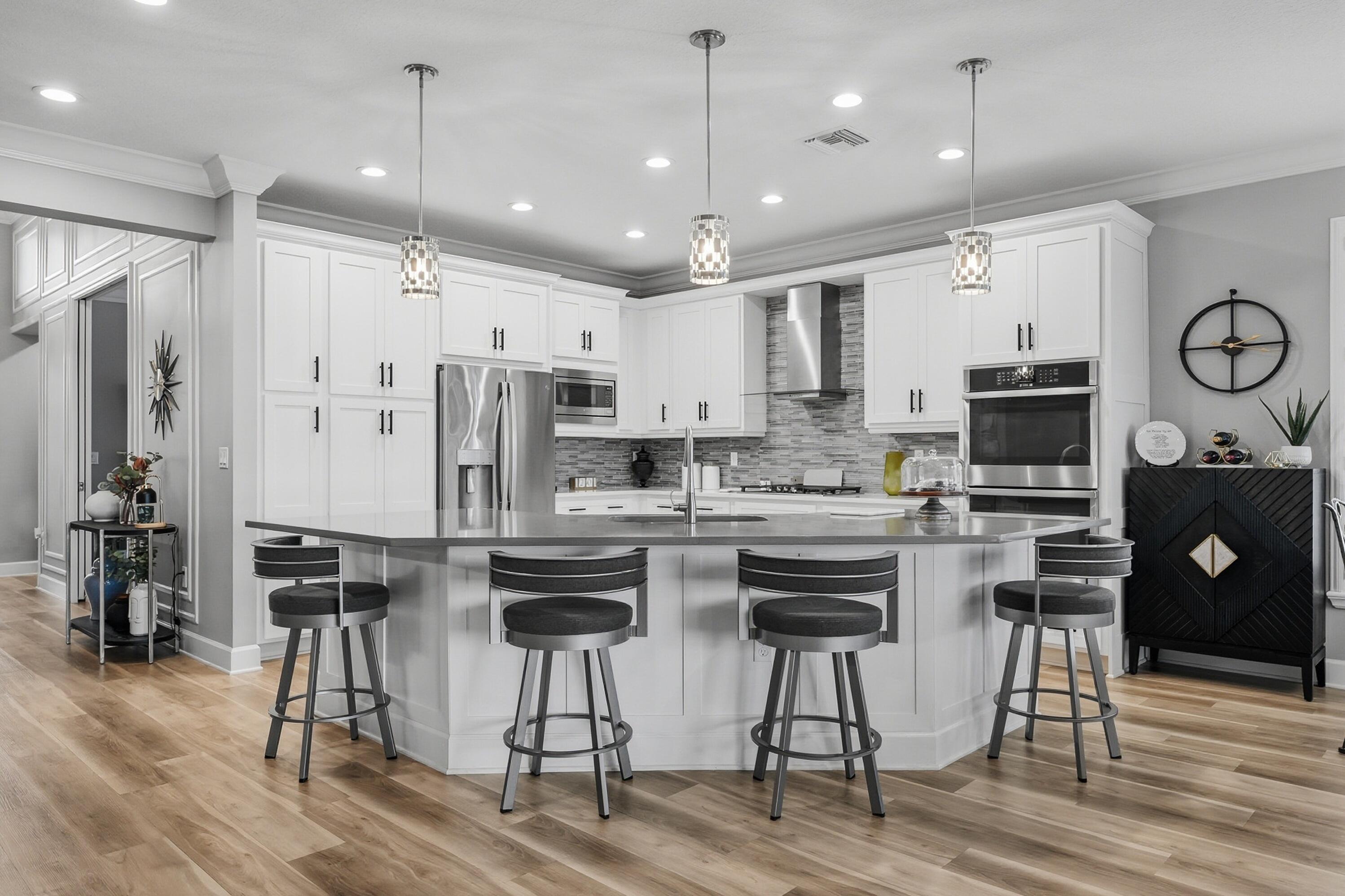 11784 Southwest Sailfish Isles Way Port St. Lucie, FL 34987 - Photo 12 of 77 a kitchen with stainless steel appliances kitchen island granite countertop a dining table chairs refrigerator and microwave