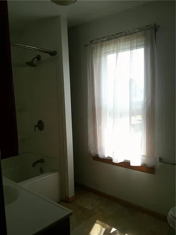 a bathroom with a bathtub a window and a shower