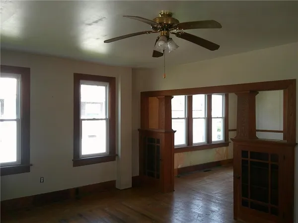 a view of an empty room with a window and wooden floor