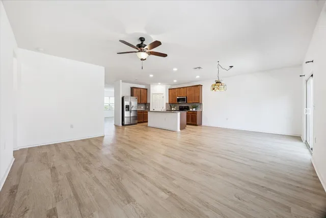 a view of a big room with wooden floor and a kitchen