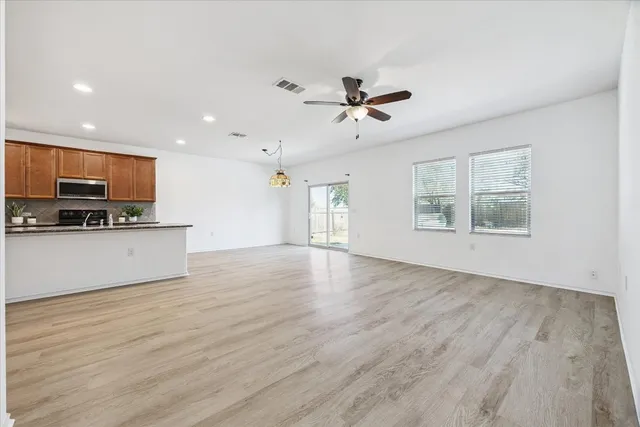 a view of an empty room with a window and wooden floor