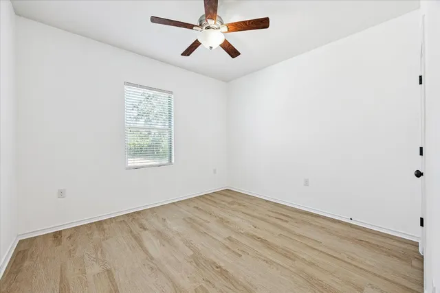 an empty room with a window and a fan