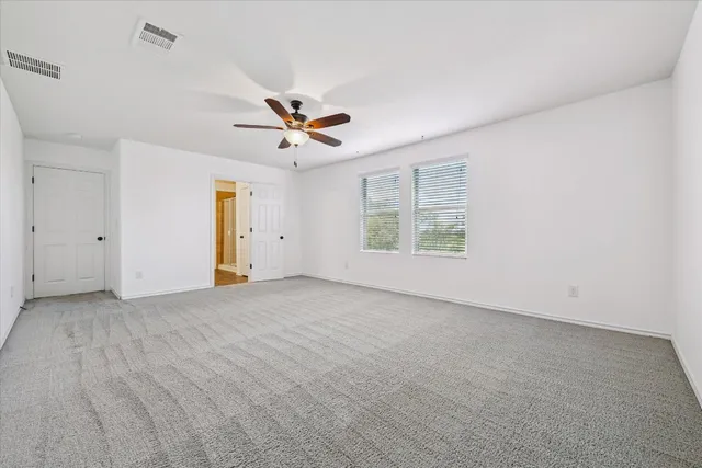 an empty room with a window and a ceiling fan