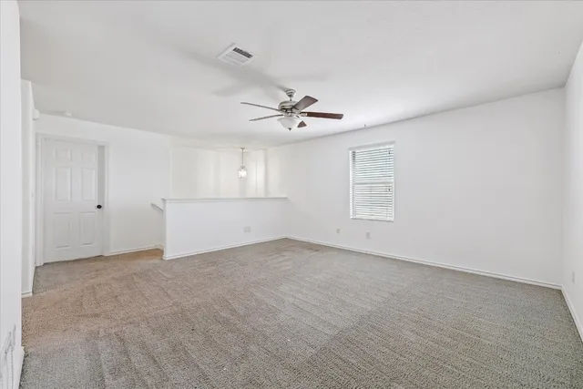 a view of an empty room with a ceiling fan and window