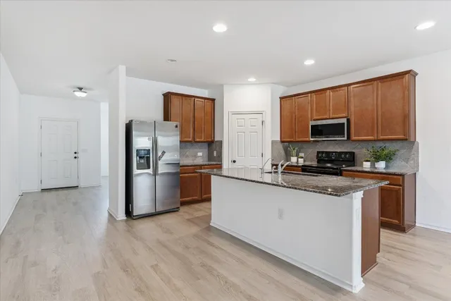 a kitchen with stainless steel appliances granite countertop a refrigerator stove microwave and sink