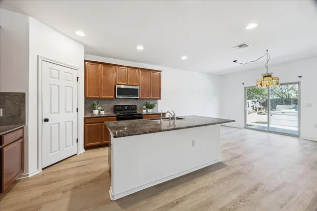 a large kitchen with stainless steel appliances granite countertop a stove a sink and a refrigerator