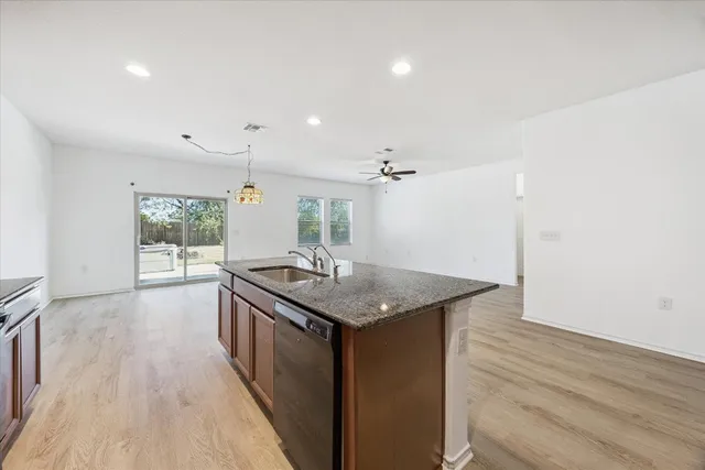 a kitchen with a stove a sink and wooden floor