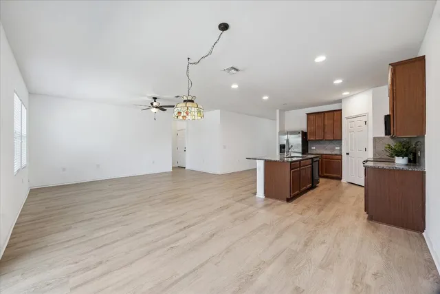 a view of a kitchen with kitchen island stainless steel appliances a sink dishwasher a refrigerator and a fireplace