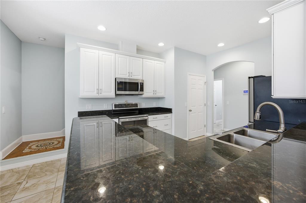 5608 Strong Point Weirsdale, FL 32195 - Photo 30 of 56 a kitchen with kitchen island granite countertop a sink and a stove top oven with wooden floor