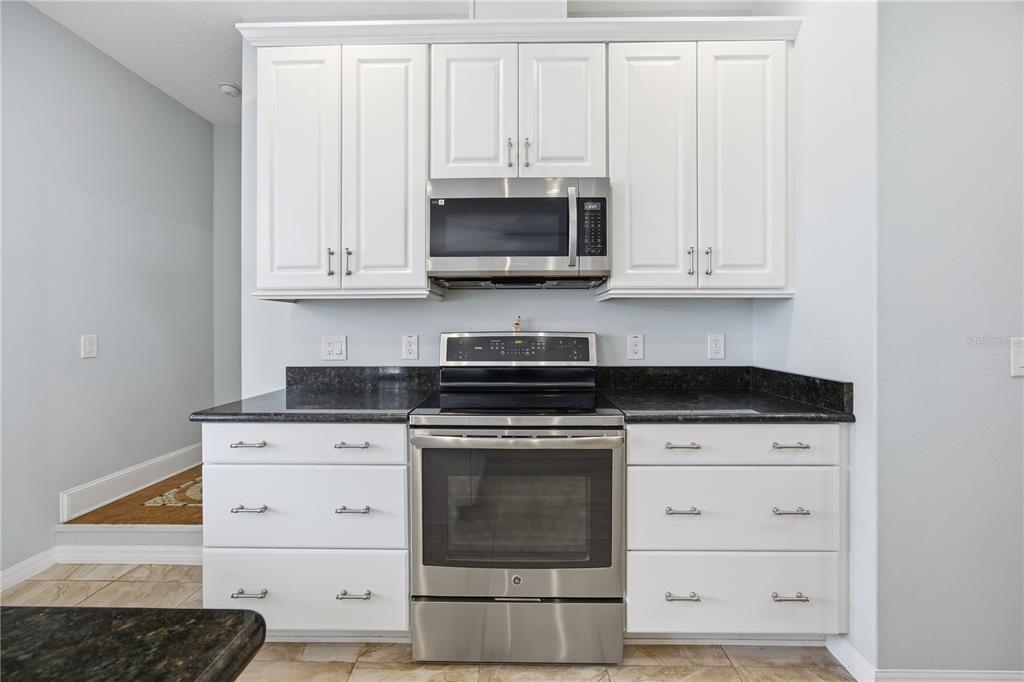 5608 Strong Point Weirsdale, FL 32195 - Photo 33 of 56 a kitchen with granite countertop white cabinets and stainless steel appliances