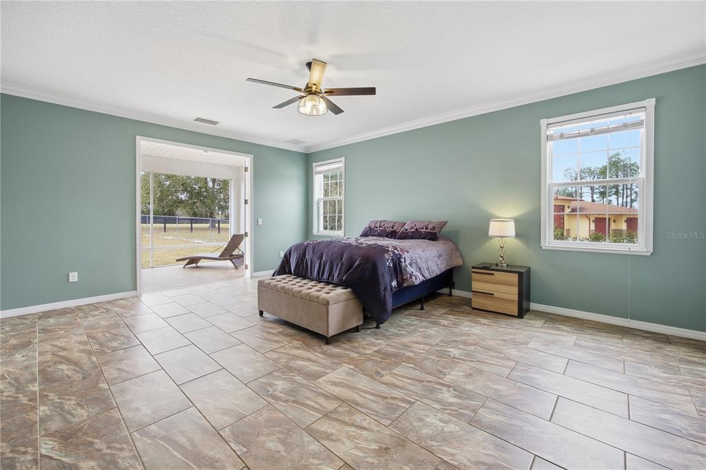 5608 Strong Point Weirsdale, FL 32195 - Photo 34 of 56 a spacious bedroom with a bed and a chandelier