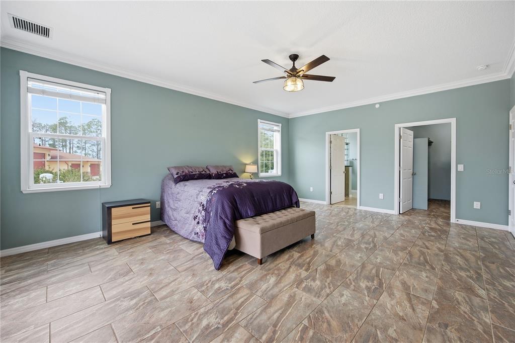5608 Strong Point Weirsdale, FL 32195 - Photo 35 of 56 a spacious bedroom with a bed and a chandelier
