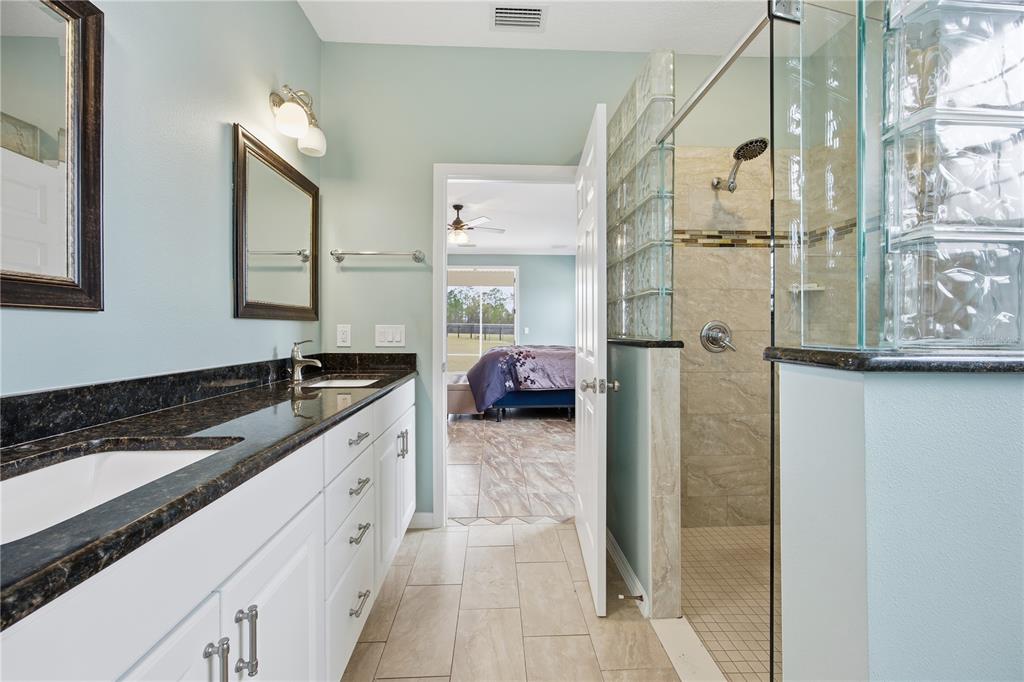 5608 Strong Point Weirsdale, FL 32195 - Photo 38 of 56 a en suite bathroom with a granite countertop sink and a mirror