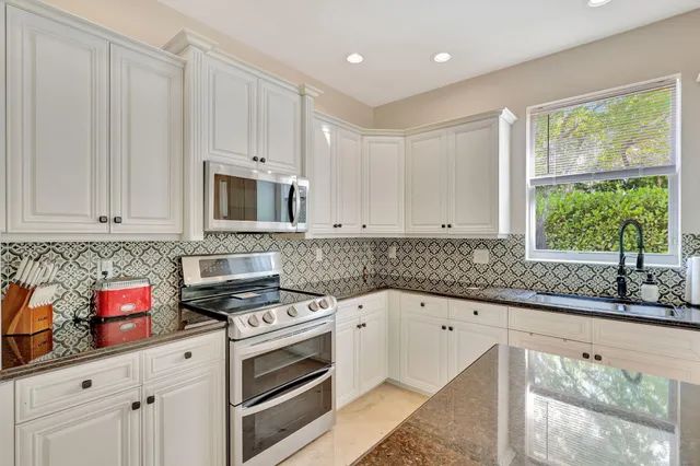 a kitchen with granite countertop white cabinets and white appliances