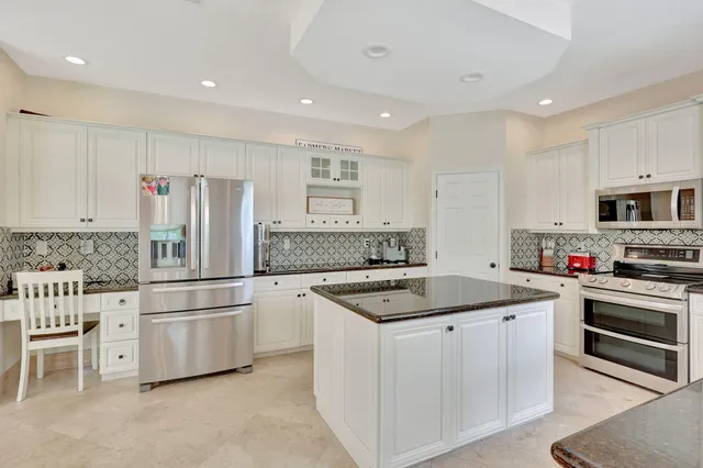 a kitchen with stainless steel appliances granite countertop a sink stove a refrigerator and white cabinets