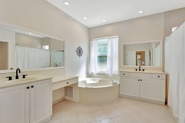 a bathroom with a double vanity sink mirror and bathtub