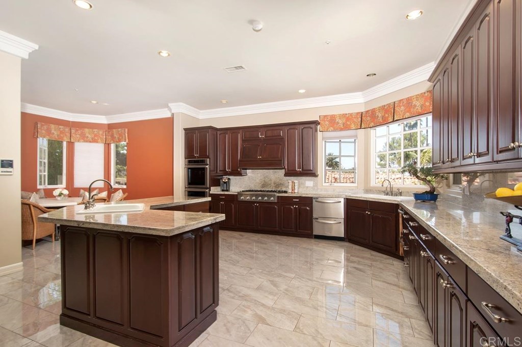 17101 Circa Oriente Rancho Santa Fe, CA 92067 - Photo 16 of 23 a kitchen with kitchen island granite countertop a sink stove and wooden cabinets