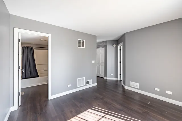 a view of an empty room with wooden floor and a ceiling fan