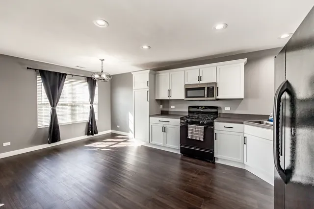 a kitchen with granite countertop stainless steel appliances and wooden floor