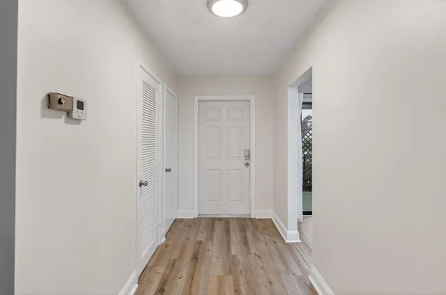 a view of an empty room with wooden floor and a window