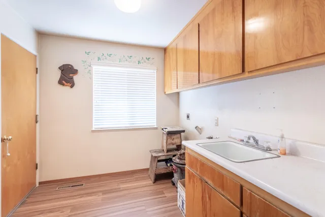 a view of a kitchen with a sink wooden cabinets and a window