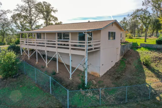 a view of a house with backyard and trees
