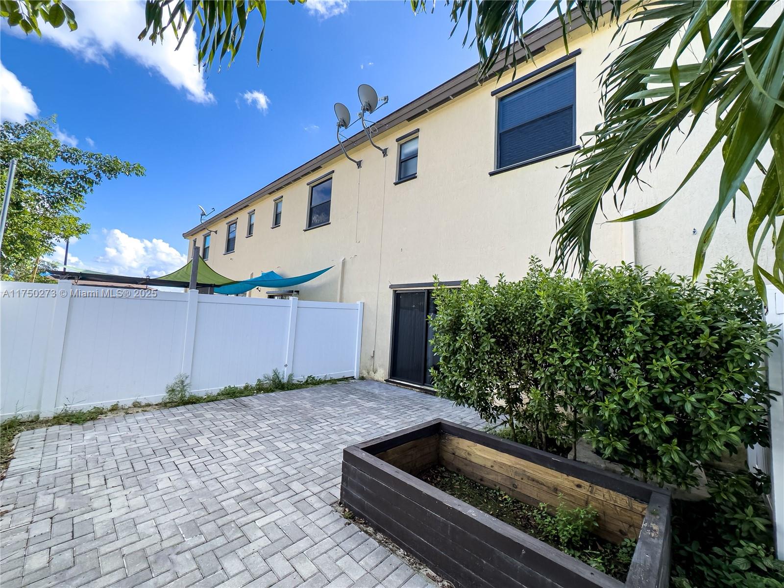 3349 West 105th Terrace, Unit 3349 Hialeah, FL 33018 - Photo 11 of 11 a backyard of a house with potted plants and palm trees