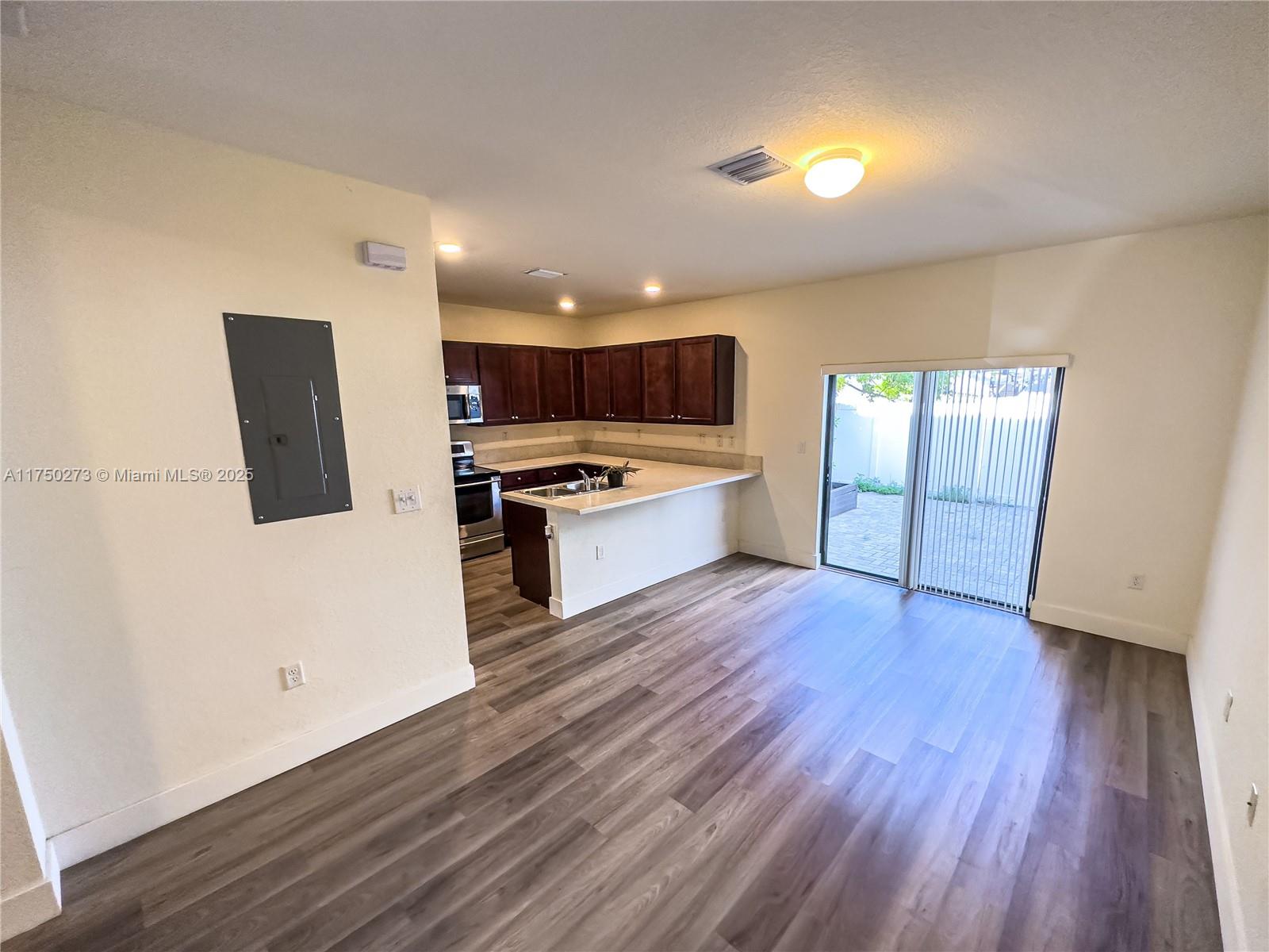 3349 West 105th Terrace, Unit 3349 Hialeah, FL 33018 - Photo 5 of 11 a view of kitchen with microwave a stove and wooden floor