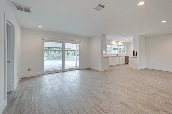 a view of an empty room with a window and wooden floor