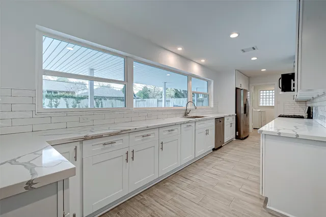 a large kitchen with stainless steel appliances granite countertop a sink and cabinets with wooden floor