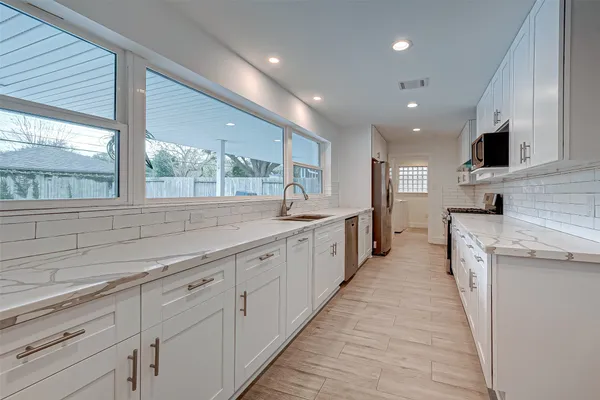 a large kitchen with stainless steel appliances granite countertop a large counter top a sink and a refrigerator