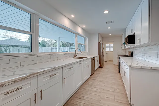 a large kitchen with stainless steel appliances granite countertop a large counter top a sink and a refrigerator