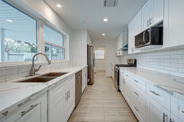 a large kitchen with stainless steel appliances granite countertop a sink and dishwasher a stove top oven with wooden floor