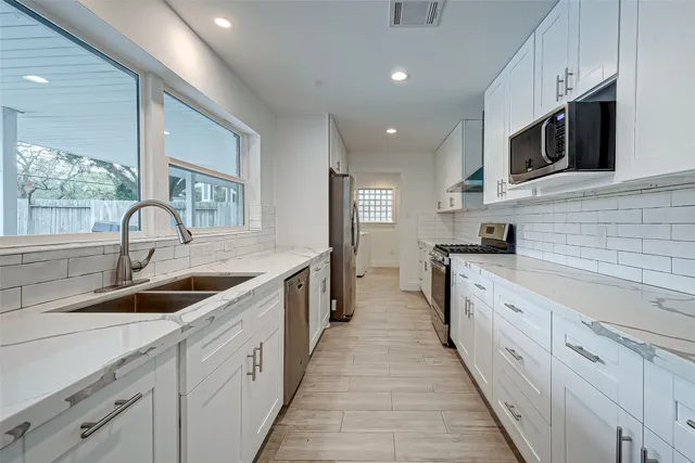 a large kitchen with stainless steel appliances granite countertop a sink and dishwasher a stove top oven with wooden floor