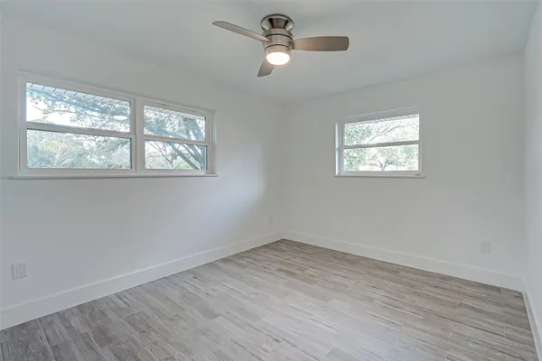 a view of empty room with wooden floor and fan