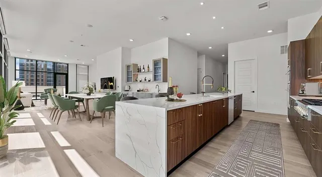 a large kitchen with stainless steel appliances a large counter top a sink a stove and a refrigerator