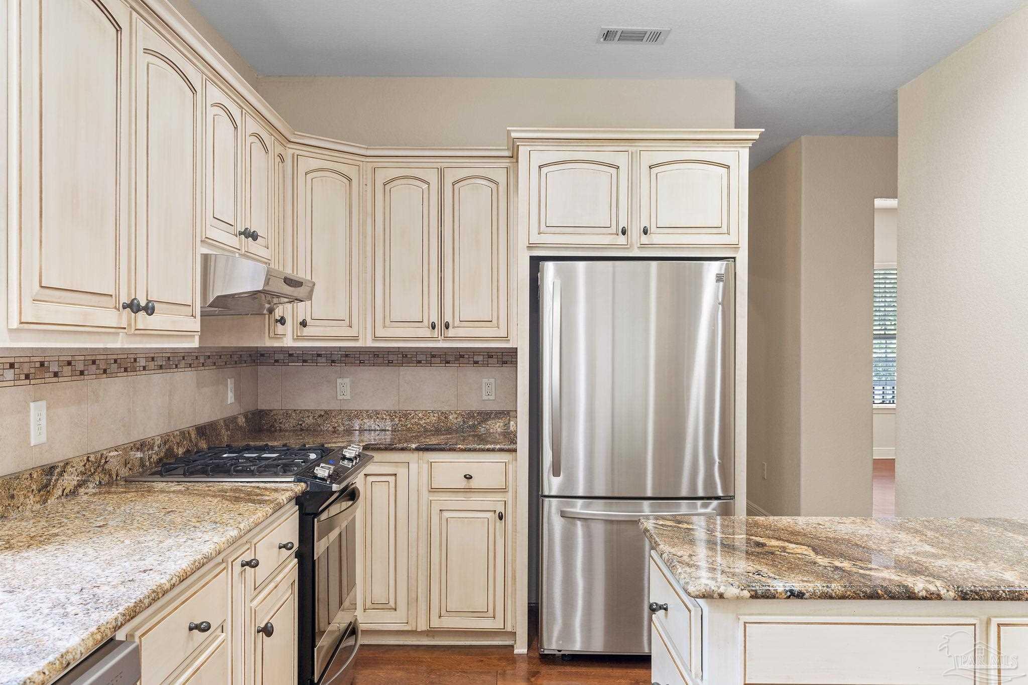 8664 Foxtail Loop Pensacola, FL 32526 - Photo 22 of 46 a kitchen with granite countertop a refrigerator sink and cabinets