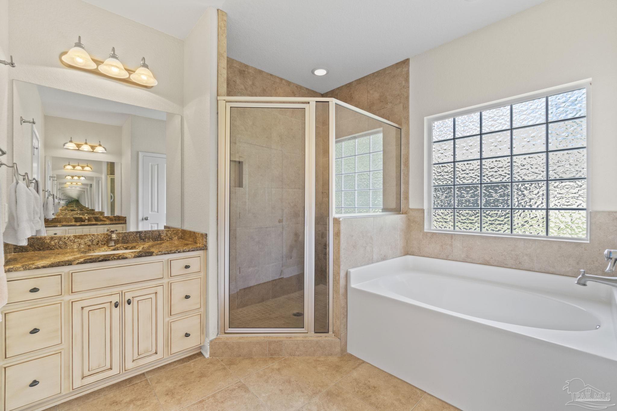 8664 Foxtail Loop Pensacola, FL 32526 - Photo 27 of 46 a spacious bathroom with a granite countertop tub sink a mirror a shower and vanity