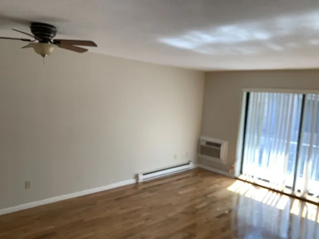 a view of an empty room with wooden floor and a window