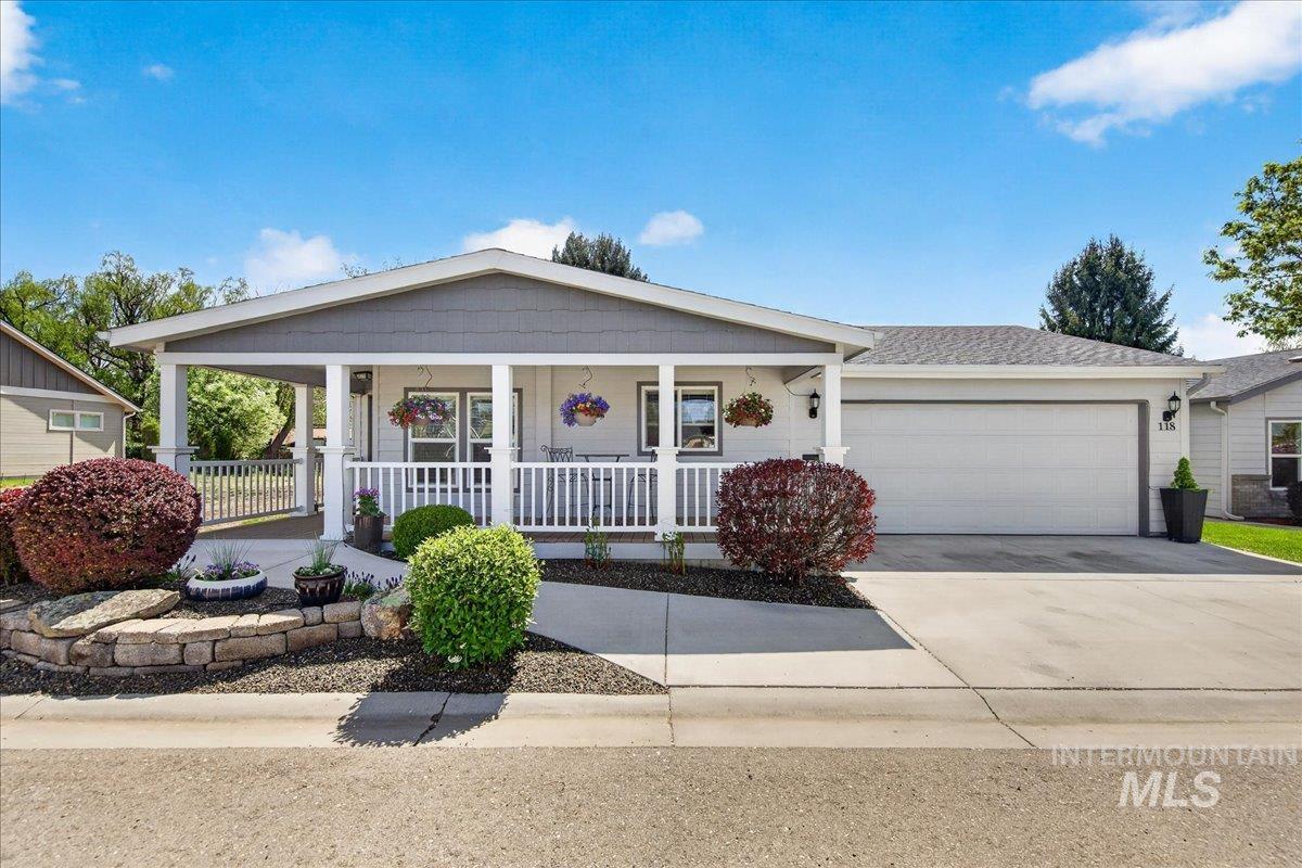 View of front facade featuring an attached garage, covered porch, and driveway