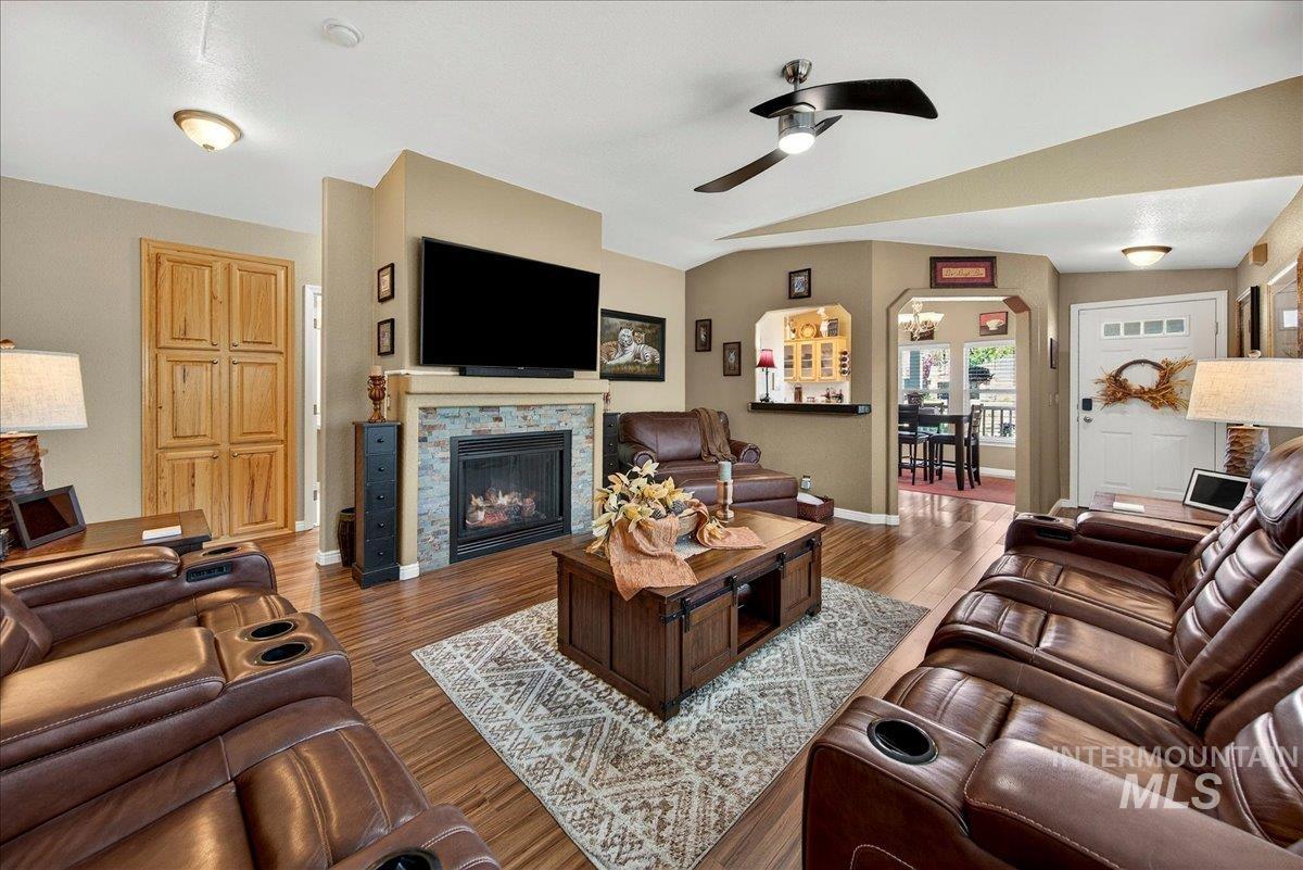 421 South Curtis Road, Unit 118 Boise, ID 83705 - Photo 11 of 49 Living area featuring a glass covered fireplace, arched walkways, dark wood finished floors, ceiling fan, and vaulted ceiling