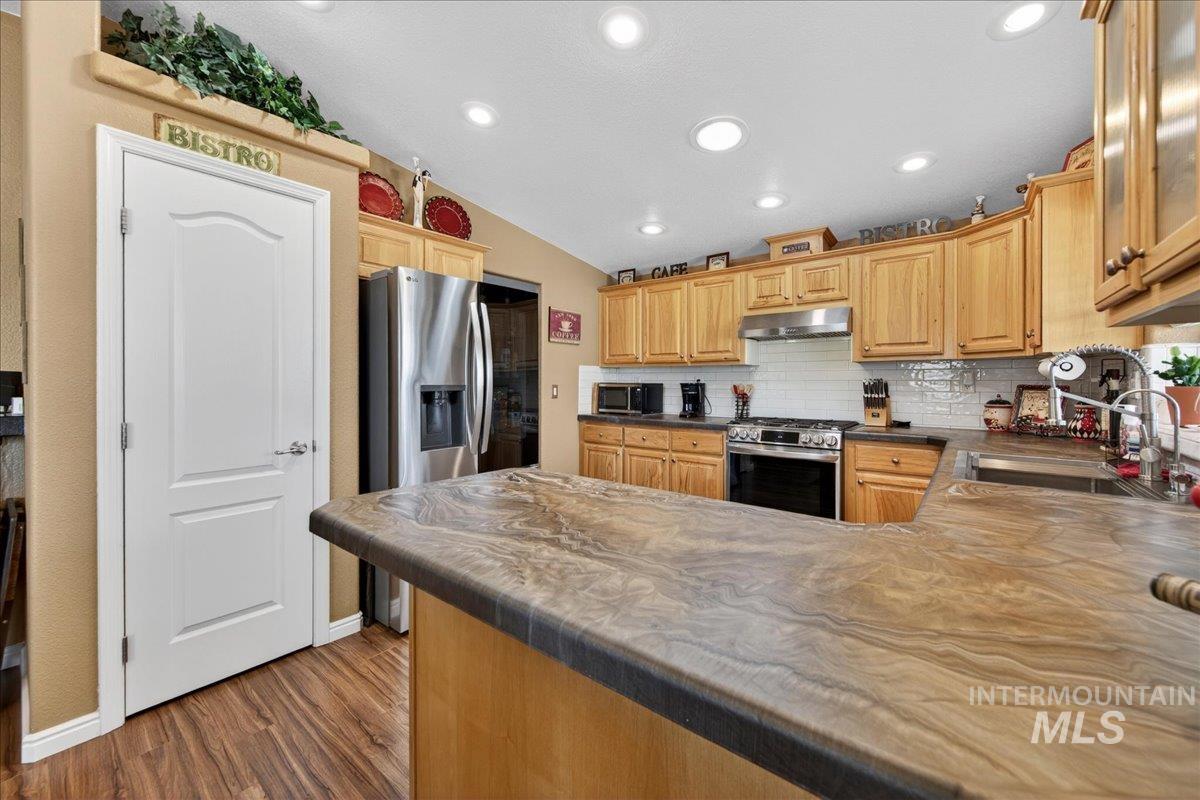 421 South Curtis Road, Unit 118 Boise, ID 83705 - Photo 17 of 49 Kitchen featuring lofted ceiling, a peninsula, stainless steel appliances, decorative backsplash, and dark wood-style floors