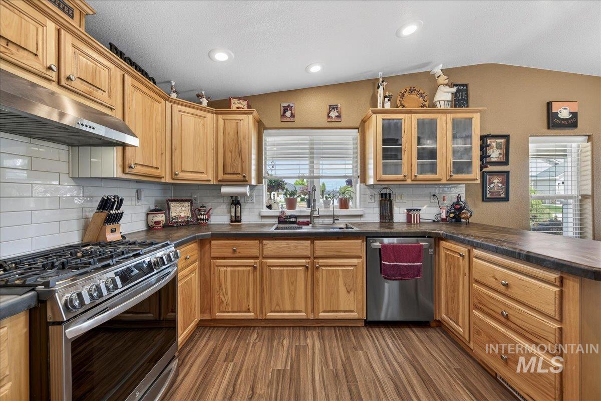 421 South Curtis Road, Unit 118 Boise, ID 83705 - Photo 19 of 49 Kitchen featuring stainless steel appliances, dark countertops, vaulted ceiling, glass insert cabinets, and a peninsula