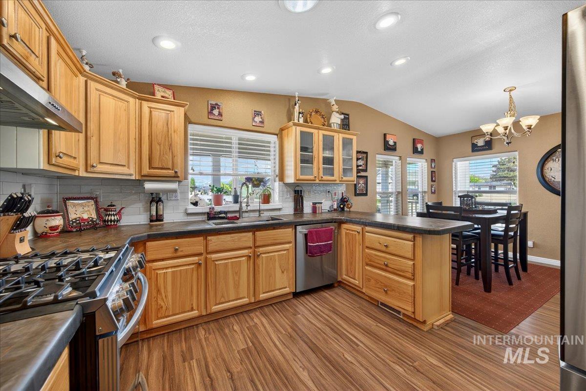 421 South Curtis Road, Unit 118 Boise, ID 83705 - Photo 21 of 49 Kitchen with a peninsula, stainless steel appliances, dark countertops, backsplash, and suspended lighting