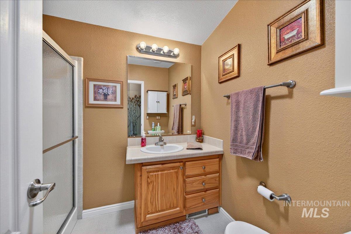 421 South Curtis Road, Unit 118 Boise, ID 83705 - Photo 23 of 49 Full bath featuring a textured wall, a stall shower, vanity, and a textured ceiling