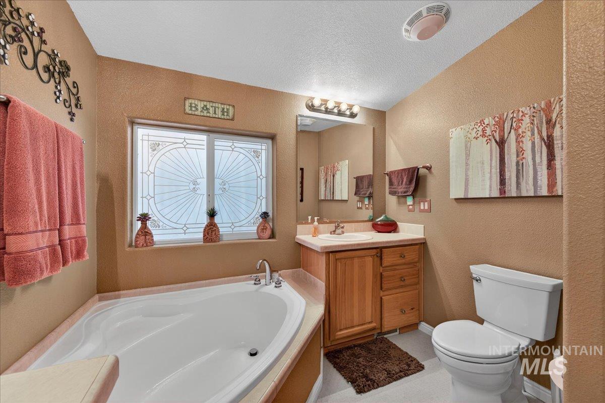 421 South Curtis Road, Unit 118 Boise, ID 83705 - Photo 33 of 49 Full bathroom with vanity, a bath, a textured wall, and a textured ceiling