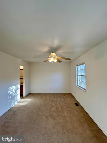 an empty room with windows and chandelier fan