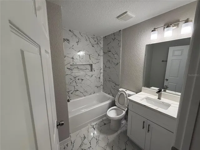 a bathroom with a bathtub shower sink vanity and toilet
